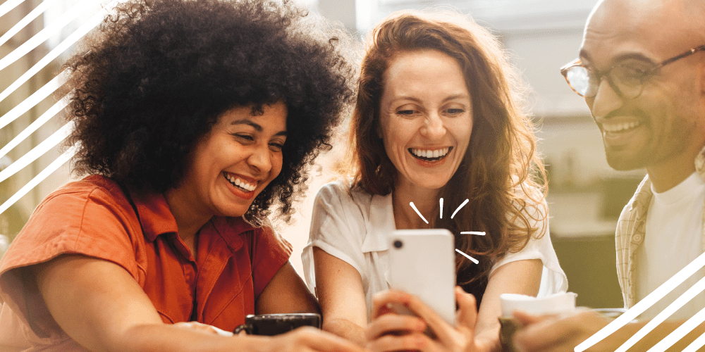 Three smiling individuals focused on their cell phones, reflecting a shared experience of happiness and engagement.