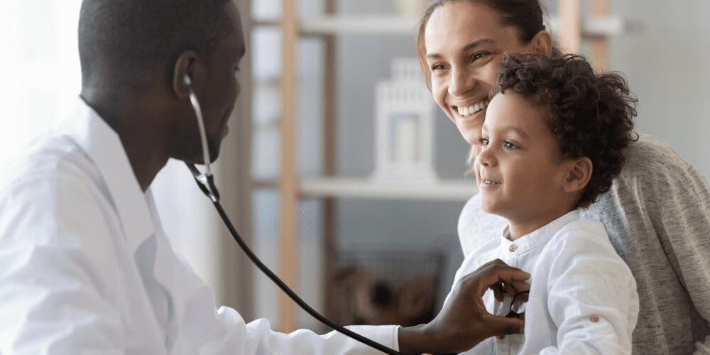 Doctor examining a kid and mom smiling at him