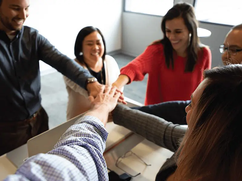 Group of people putting their hands together in the middle.