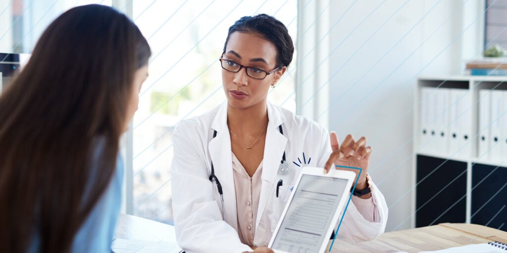 Female Doctor Holding Tablet With Patient to Show Healthcare Update, Report and Information