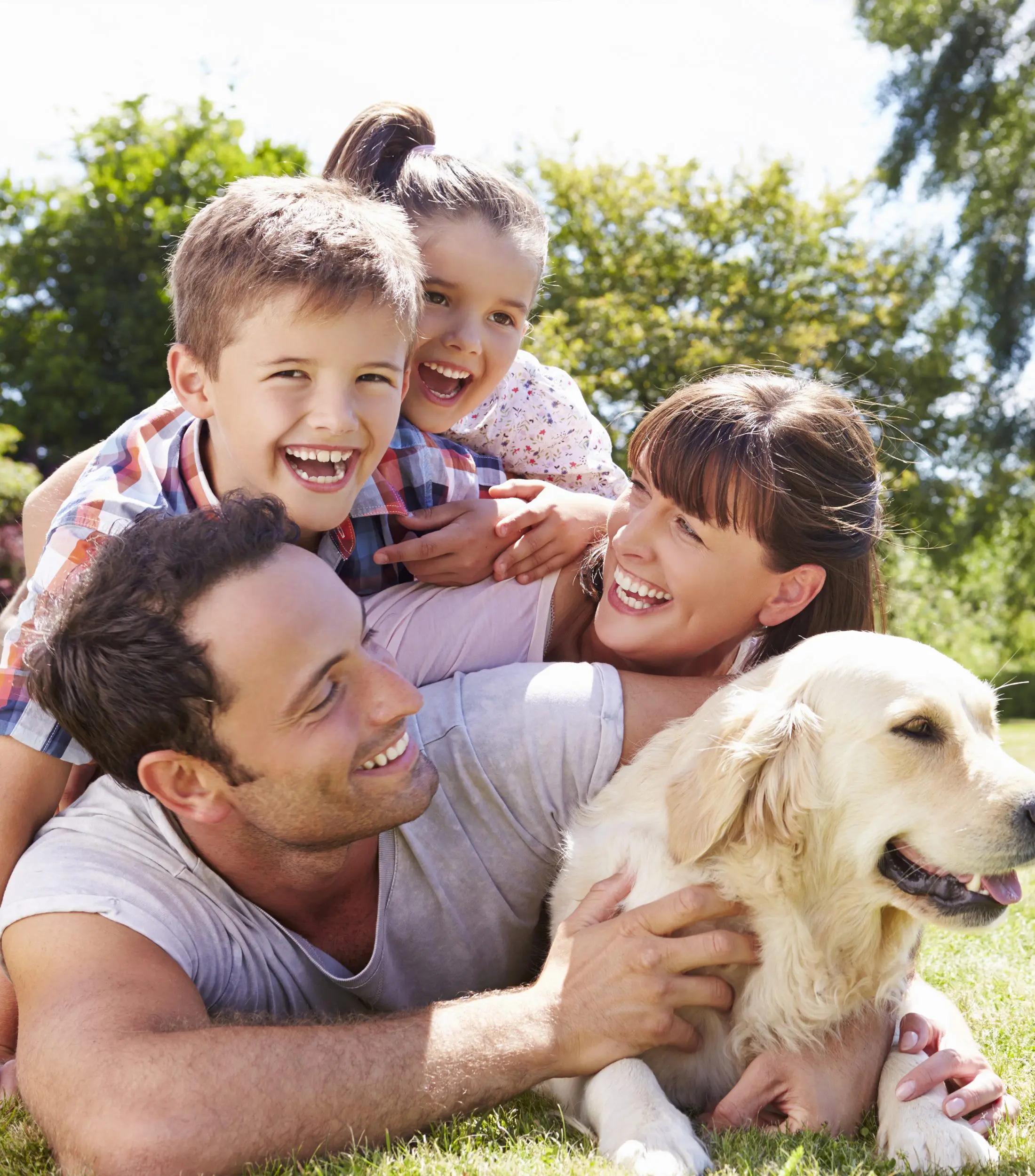 Family Relaxing On Grass With Pet Dog