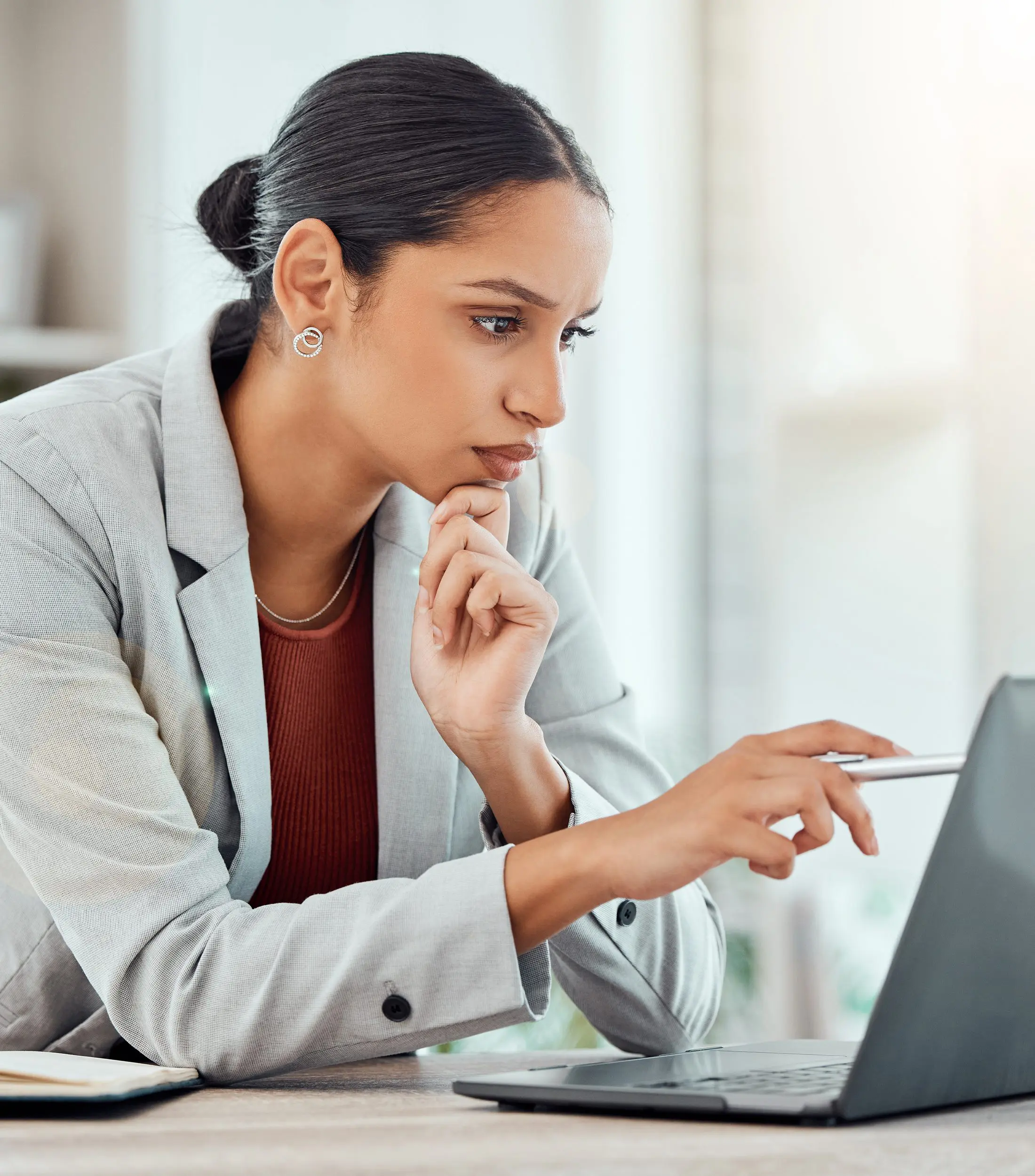 Professional Businesswoman Looking at a Laptop With a Pen