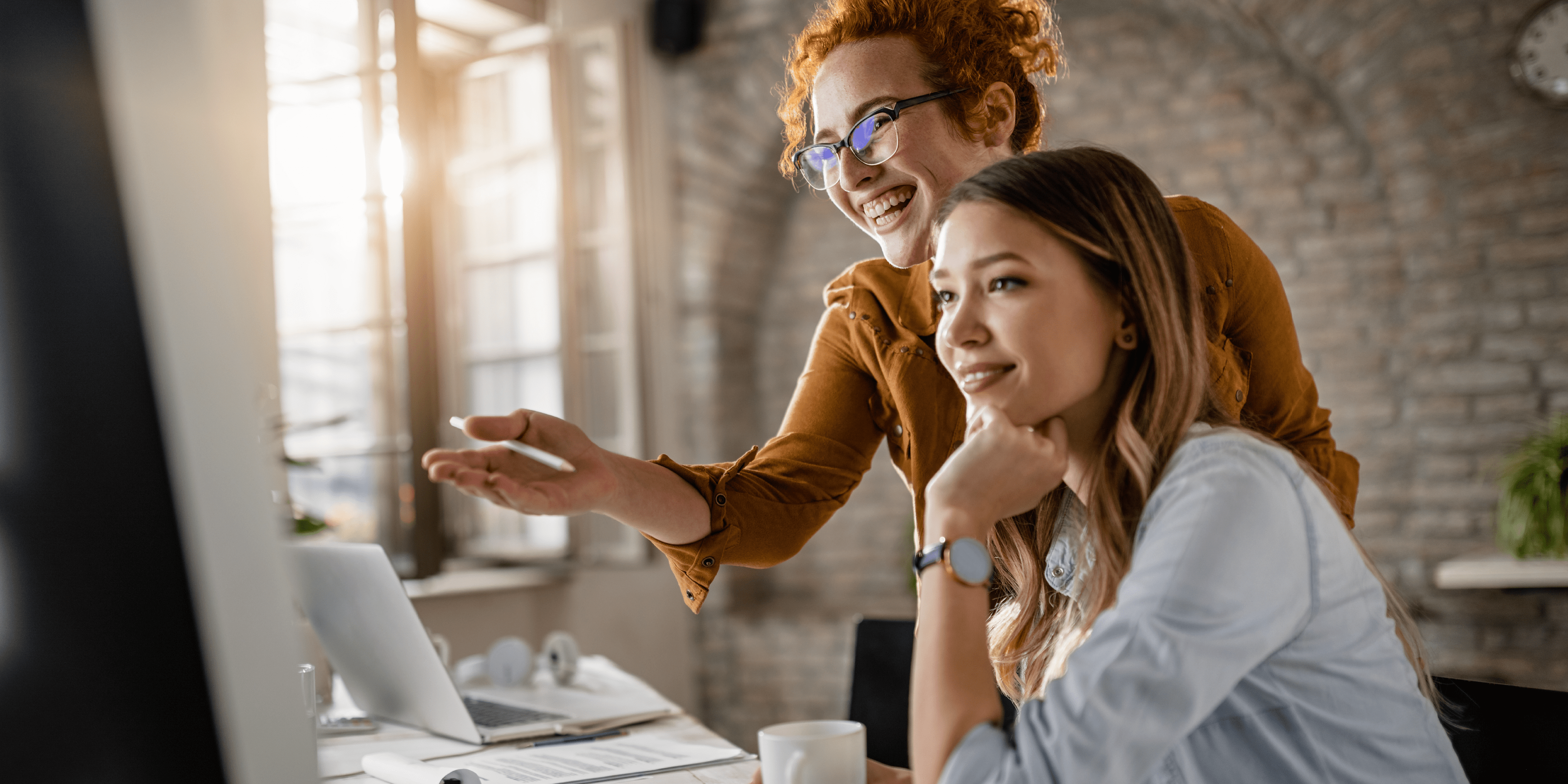 two women smiling and looking at a computer screen