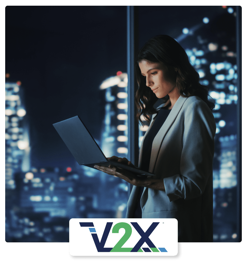 V2X Case Study Hero - Successful Young Businesswoman Standing and Using Laptop in a Big City Modern Office at Night