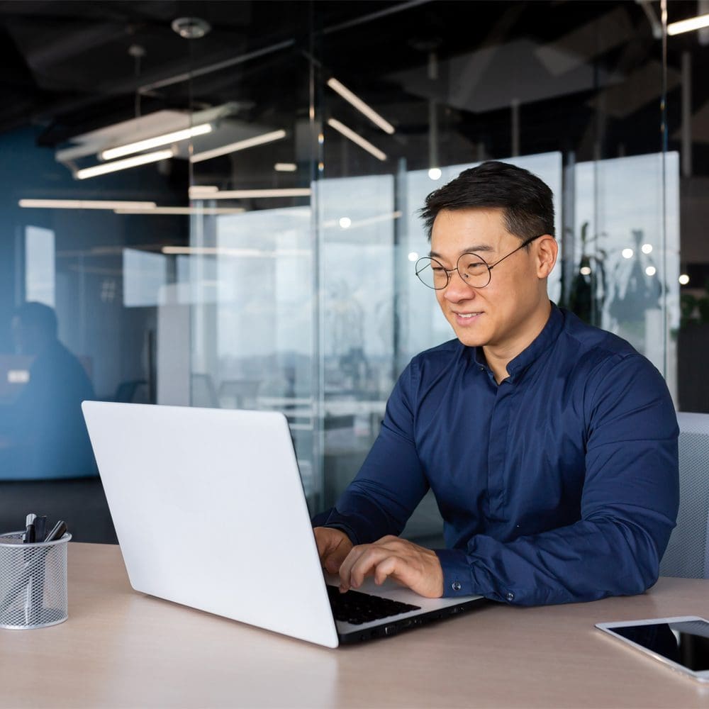 Engaged Male Working Inside Office Using Laptop and Smiling