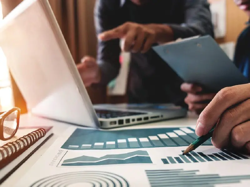 Employees working together looking at data printed on the desk.