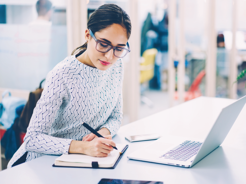 A woman with glasses jotting down notes.