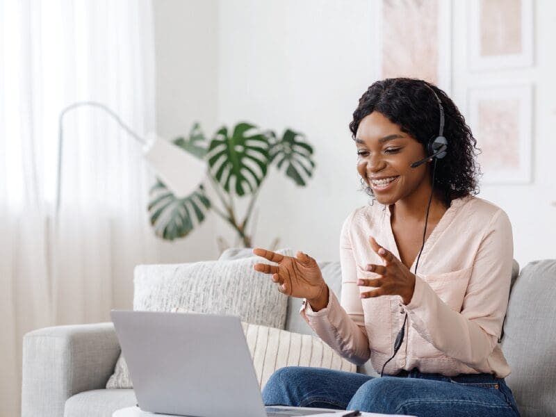 Remote employee working from couch smiling at the computer