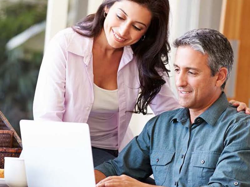 middle age couple looking at laptop at home