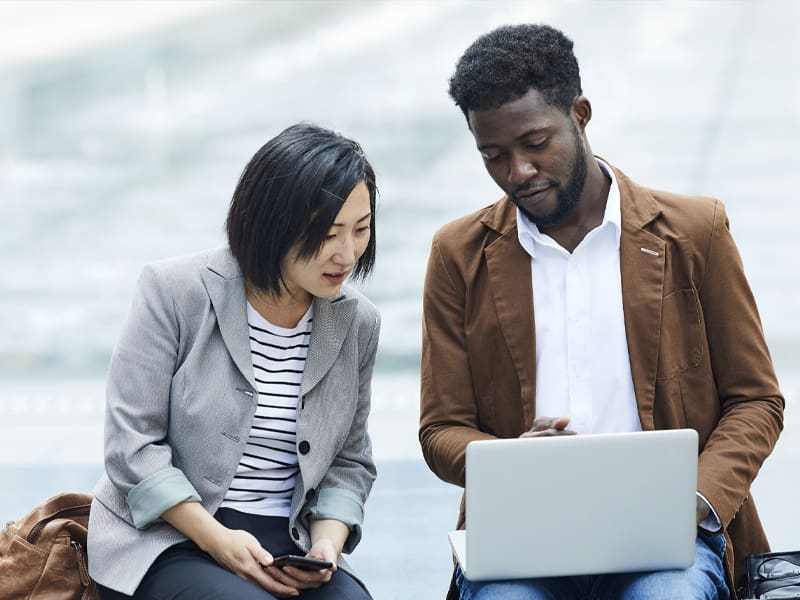 Portrait of Two Young People Using Laptop Together Outdoors – Resource Thumbnail