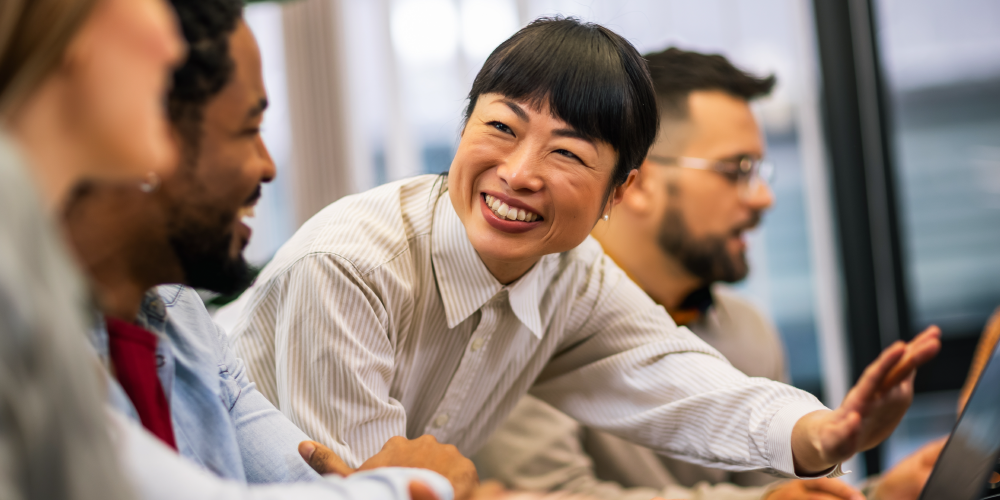 A woman smiling while engaging in conversation with her colleagues in a professional setting.