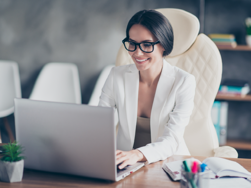 Woman smiling at a computer with sunlight coming in the window