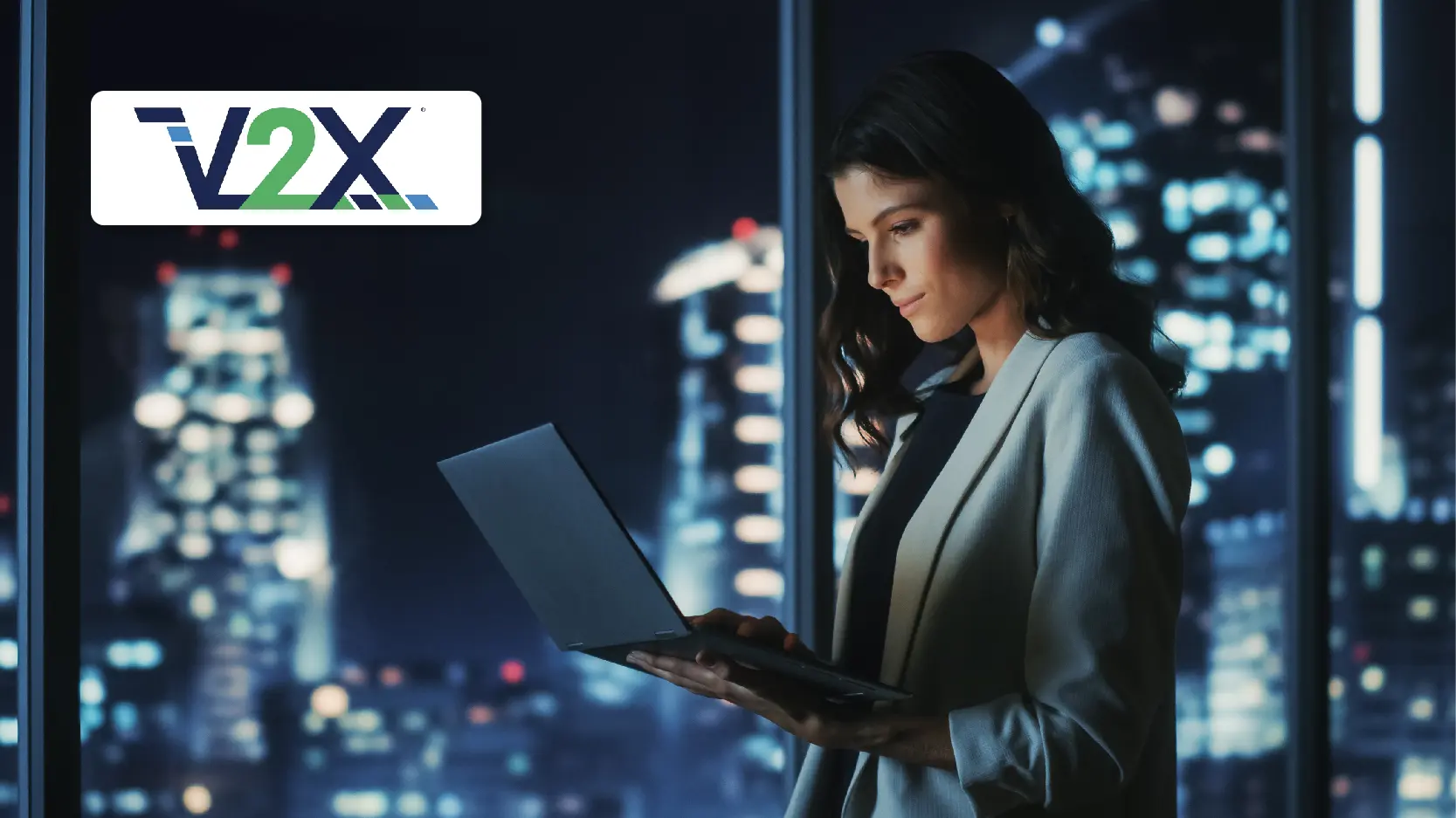 V2X Case Study Resource Image - Successful Young Businesswoman Standing and Using Laptop in a Big City Modern Office at Night