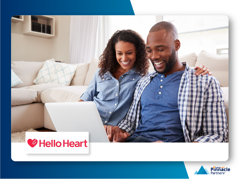 Two people smiling while looking at a computer screen on the couch