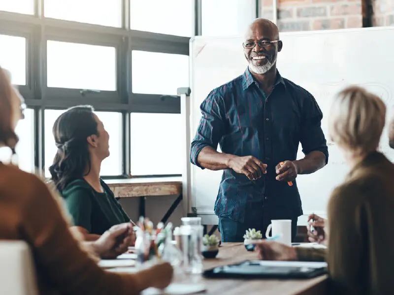 Group of individuals at a meeting smiling and engaging with one another.