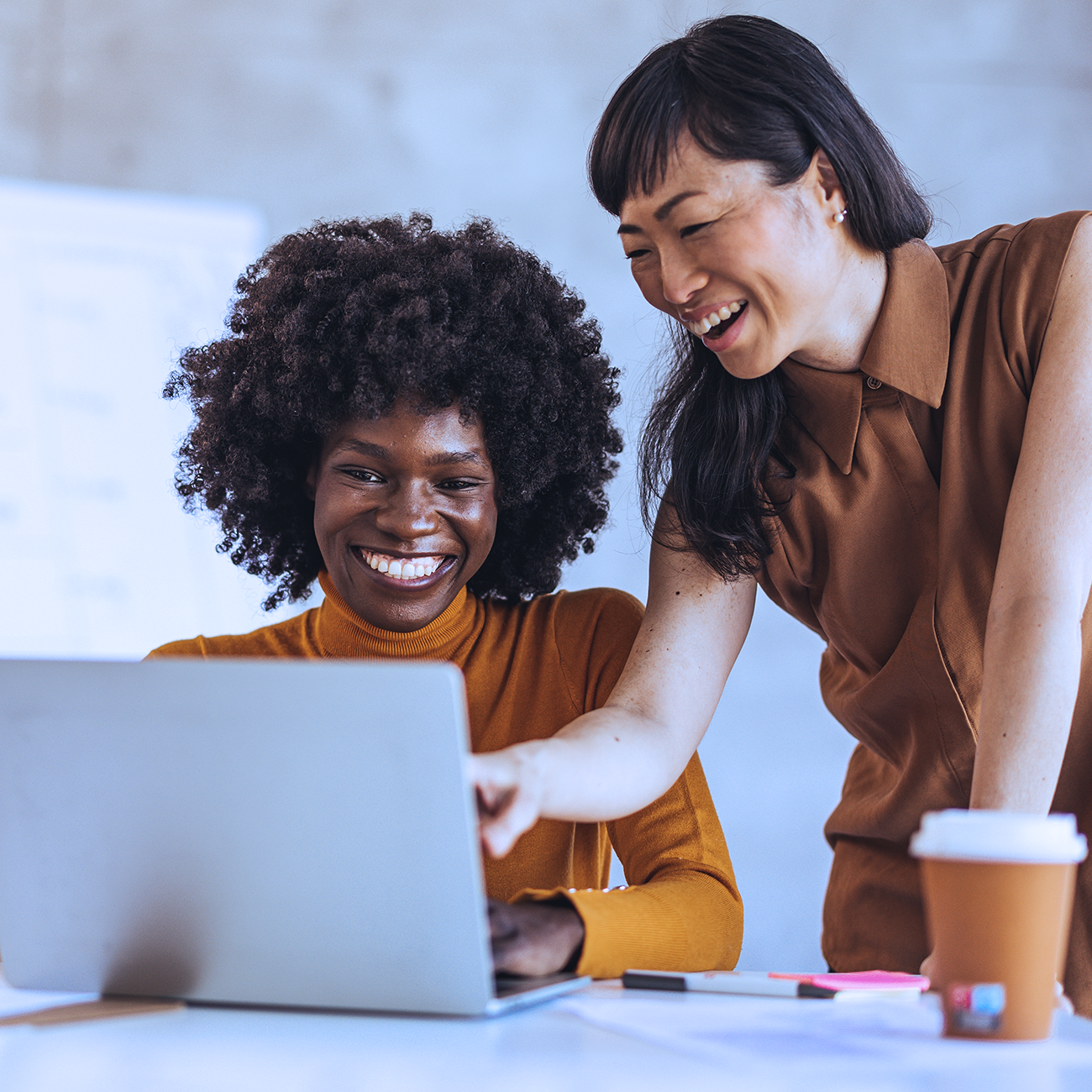 Two women smiling and looking at a computer screen