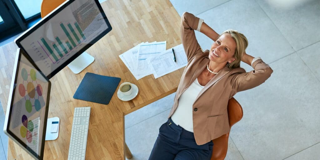 woman in an office environment laying back in her chair looking at a computer screen