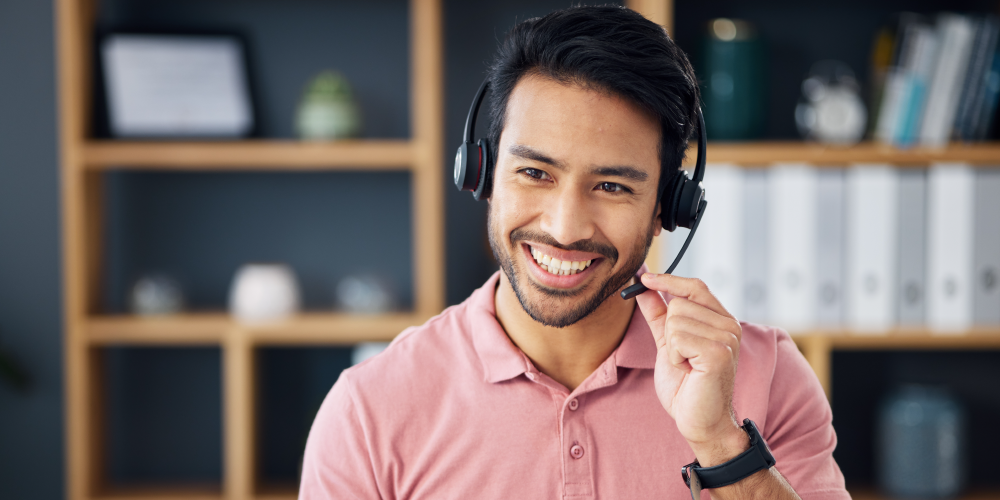 A smiling man wearing a headset, exuding positivity and engagement while interacting with others.