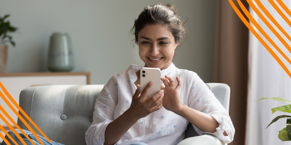 A woman seated on a couch, engaged with her cell phone, exuding a relaxed and focused demeanor.