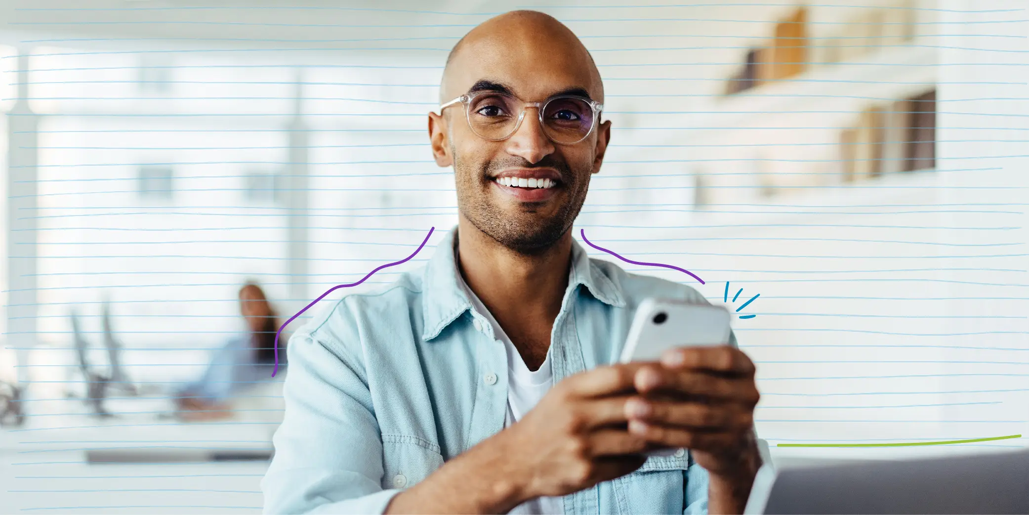 Happy Business Man Using a Smartphone While Sitting With a Laptop in His Workplace