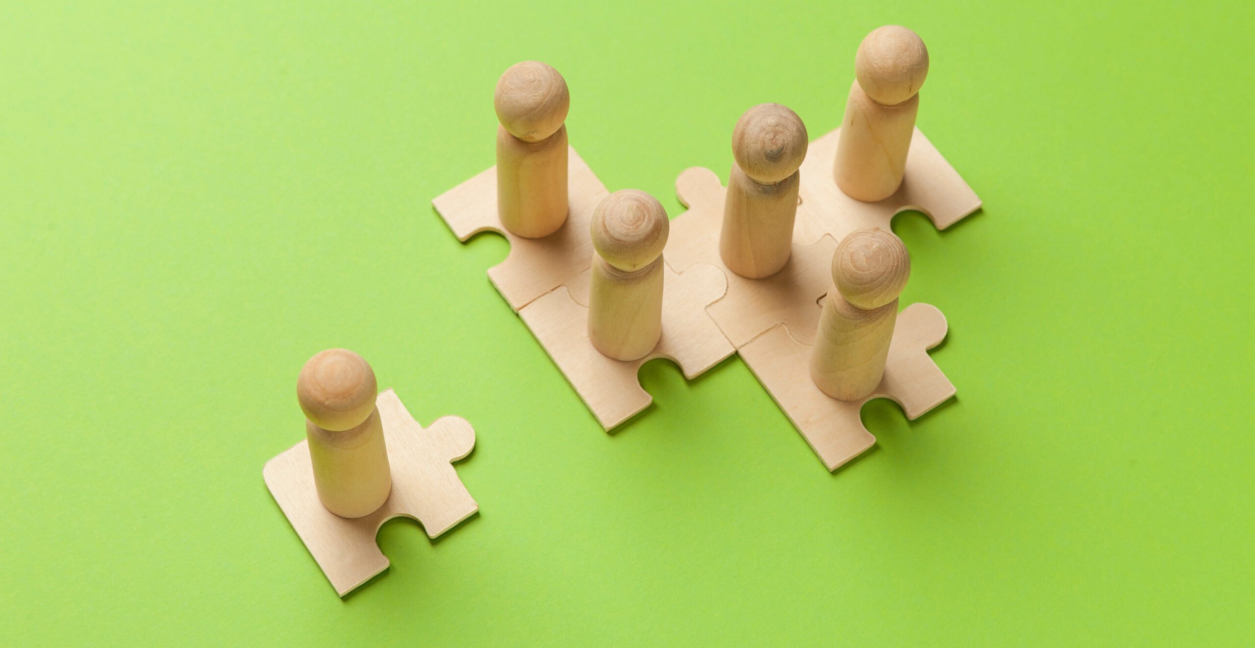 Wooden figures on puzzles on green background as a symbol of tea