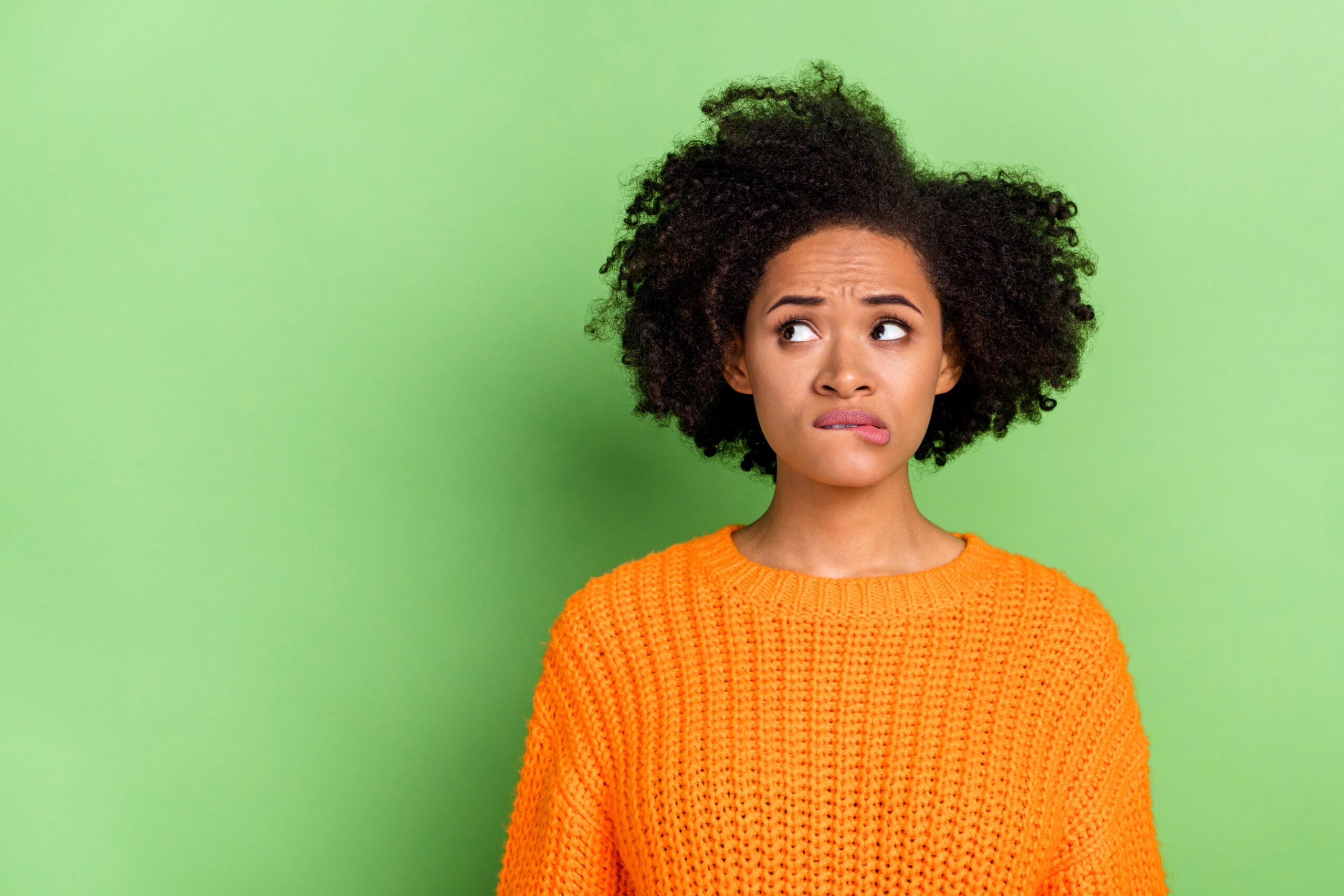 Photo of stressed young wavy hairdo lady look promo wear orange pullover isolated on green color background