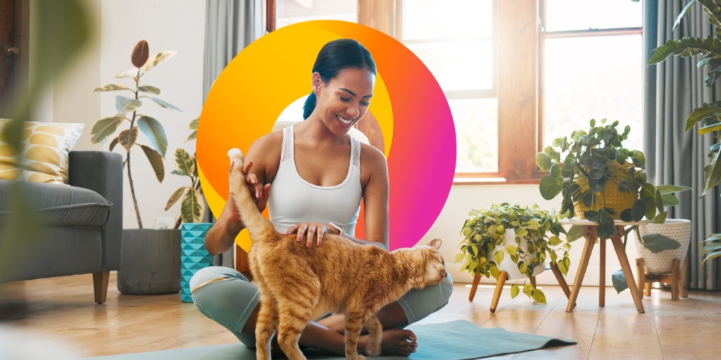Woman sitting on yoga mat petting a cat